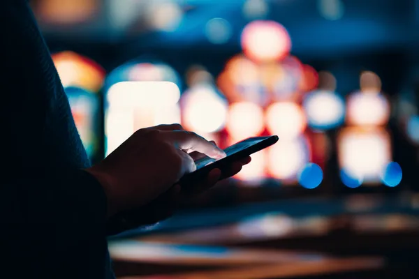 A stylish woman beside vibrant slot machines displaying glowing sevens, showcasing the variety of top slots at D63.